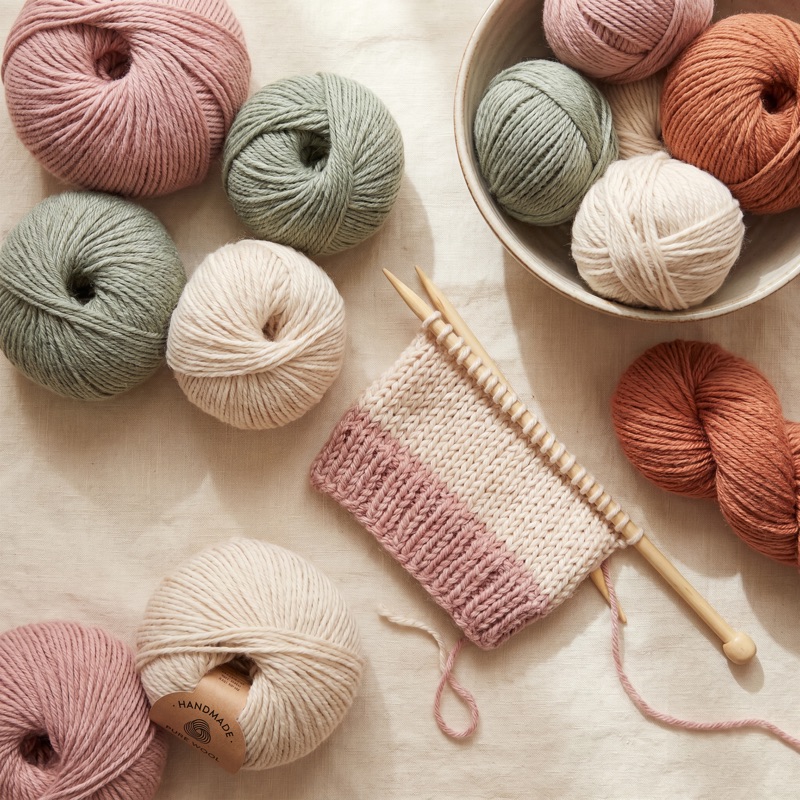 Balls of wool in soft pastel shades with knitting needles